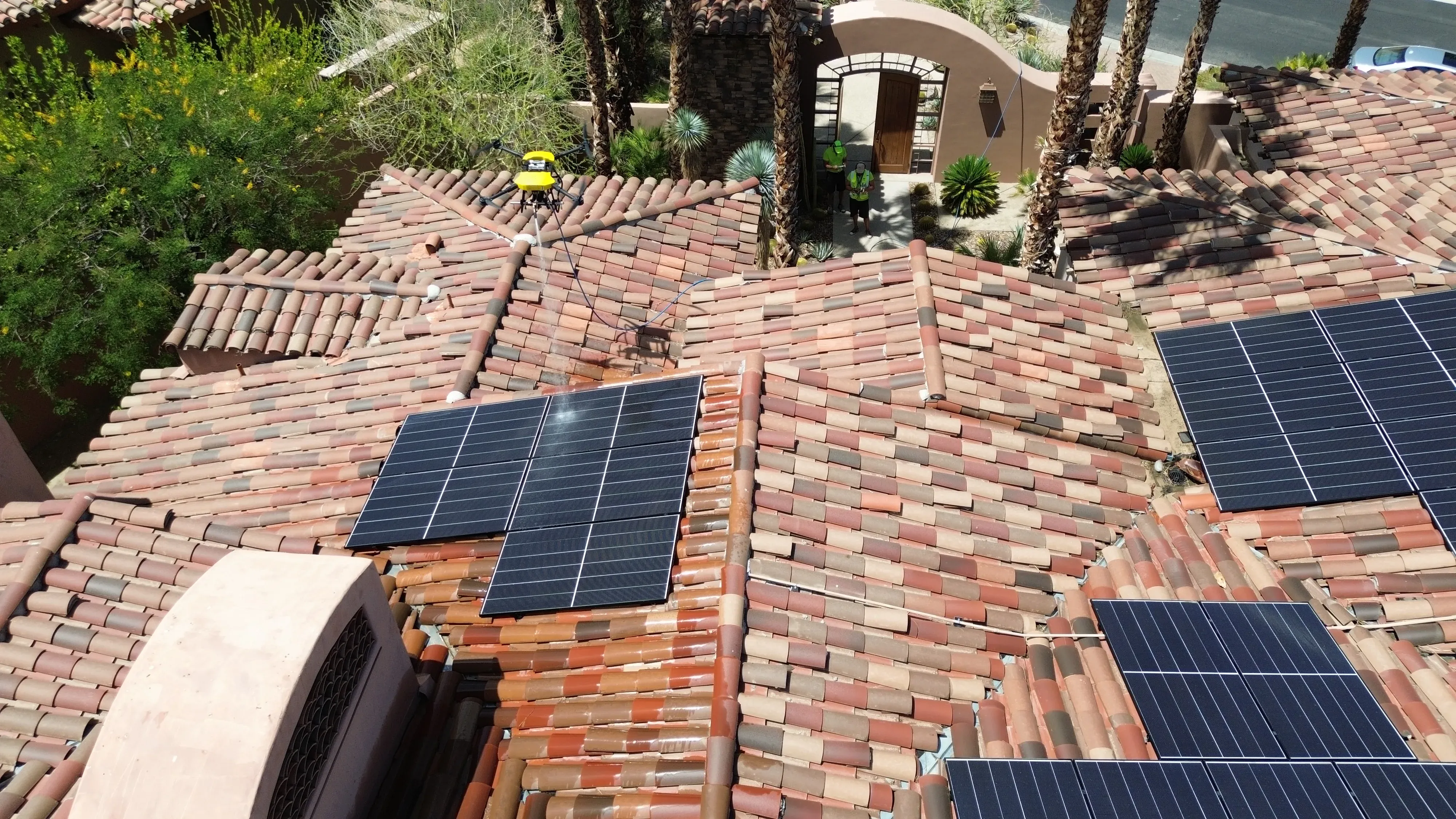 High-angle aerial view of a residential rooftop with a black solar panel array laid across the surface
